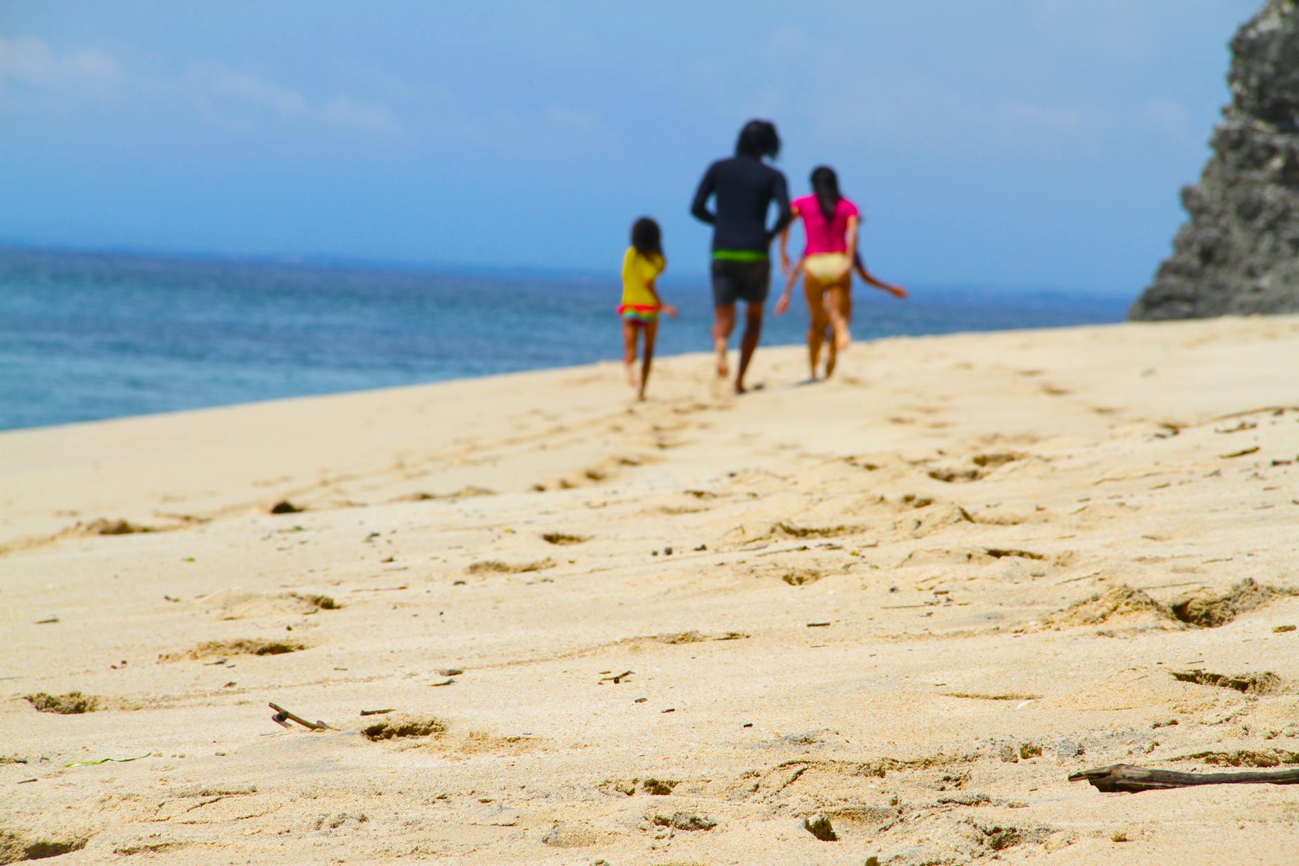 man woman and girl walking on seashore near body of water